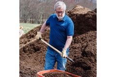 Man holding shovel picking up dirt.